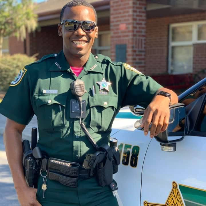 Ja’vion Brown smiling beside a patrol vehicle